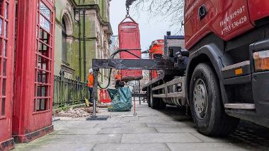 Telephone box being lifted by a crane on a truck